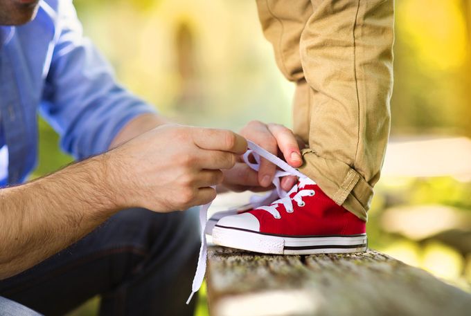 A man tying a pair of red sneakers