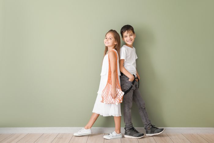 A boy and a girl standing back-to-back.