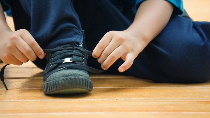 A boy tying his shoelaces.