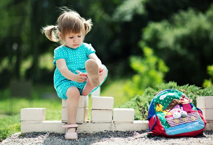 A little girl putting on kids' arch support sandals.