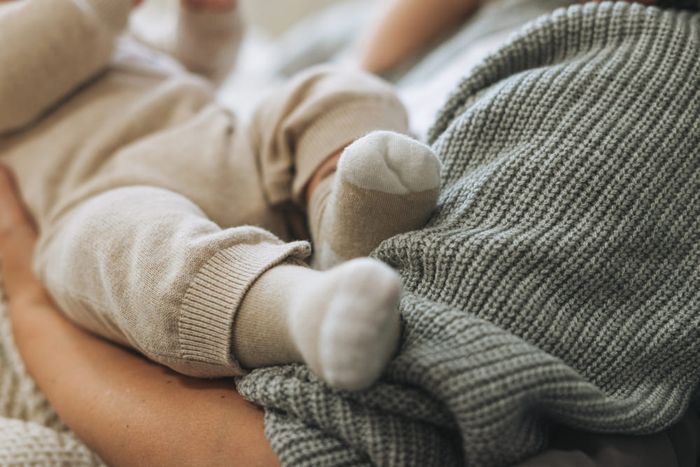 A woman holding a baby wondering if newborns should wear socks.