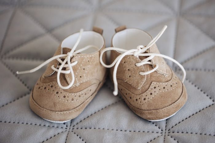 A pair of baby shoes sitting on top of a bed.