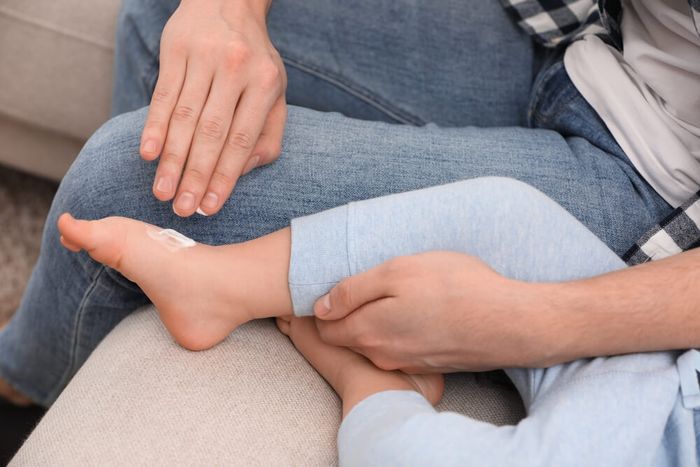 A parent applying ointment to a toddler's foot for possible conditions like feet peeling, etc.