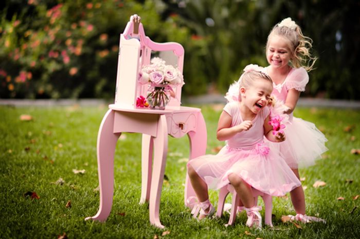 Two little girls in pink dresses playing in the grass - Top 5 Cute Pink Shoes for Little Girls