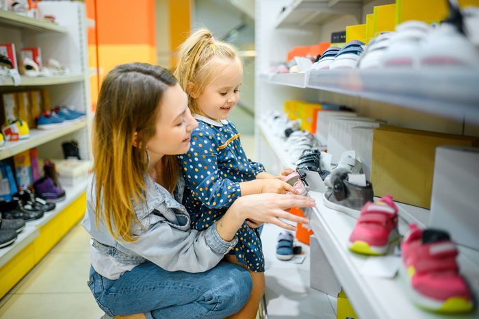 A mother looking through orthotic-friendly kids' shoes with her daughter at a store