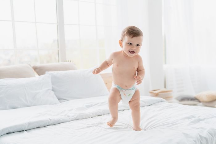 Baby's sweaty feet: a toddler walking barefoot across a bed.