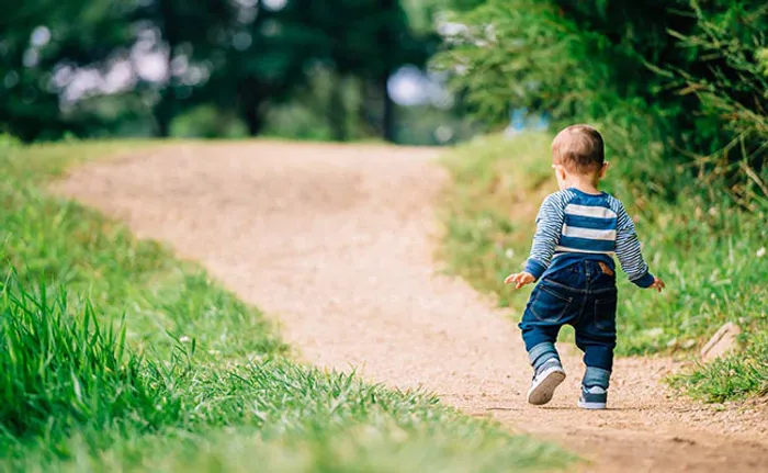a little boy running down a dirt road
