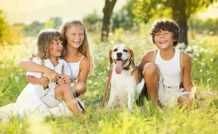 three children and a dog sitting in the grass