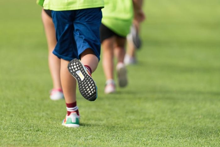 A kid running on the field while wearing adaptive footwear.