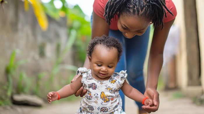 A woman is holding a small child's hand.