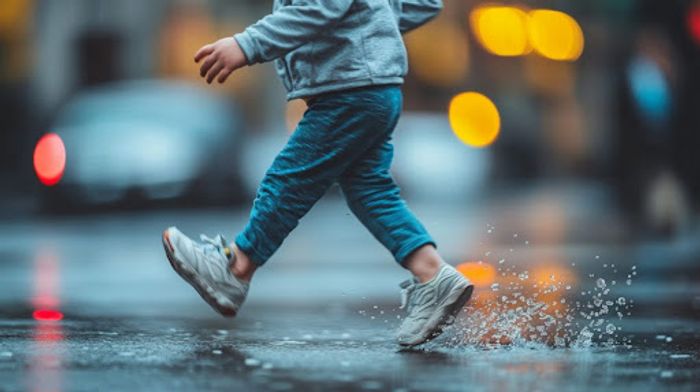 A child walking in the rain on a city street.