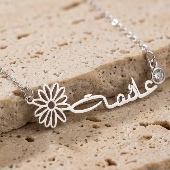 a close up of a عائشة name necklace in Silver on a stone