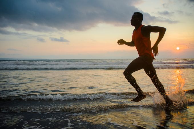 Barefoot runner on a beach during sunset