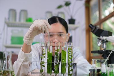 a woman in a lab coat holding up some plants