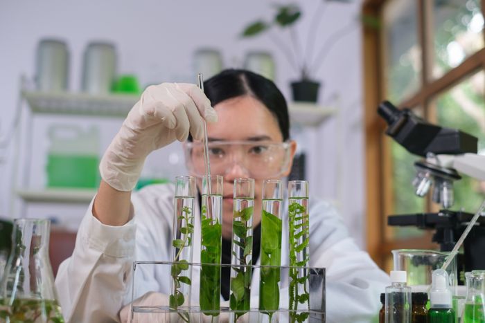 a woman in a lab coat holding up some plants