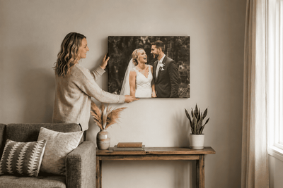 A woman hanging up a canvas frame in her living room.