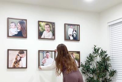 A woman designing a gallery wall layout with maple frames.