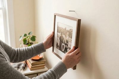 a woman is holding a picture on a wall