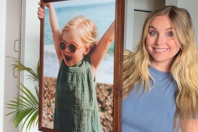 A woman holding up a wooden picture frame.
