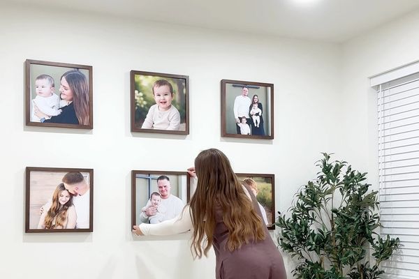 A woman designing a gallery wall layout with maple frames.