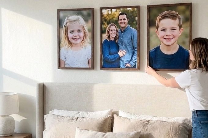 A woman setting up portraits on her bedroom wall.