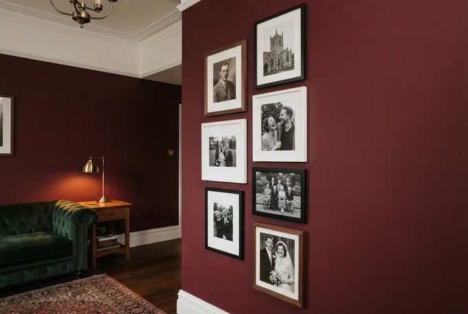 a living room with red walls and pictures on the wall