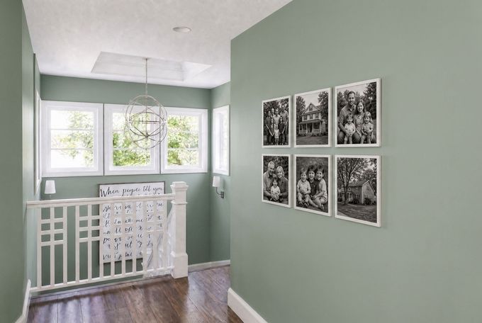 a hallway with green walls and pictures on the wall