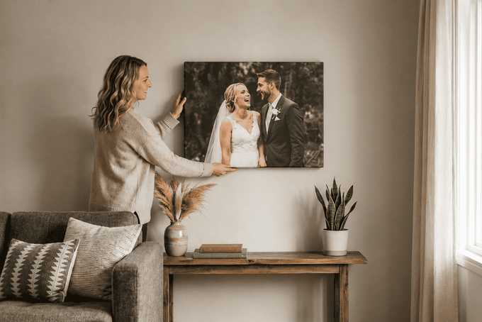 A woman hanging up a canvas frame in her living room.