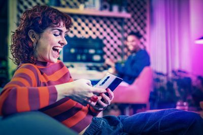 a woman laughing while looking at a cell phone