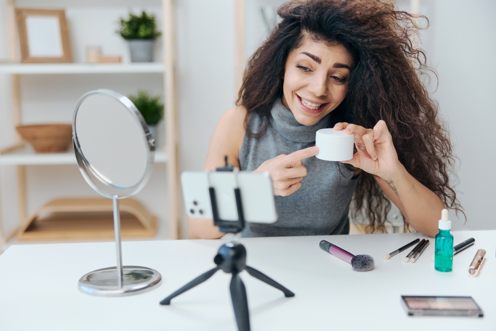 Woman filming herself with makeup products to create a product explainer video for her business