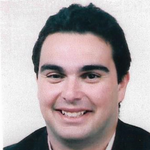 a man in a suit and tie smiling at the camera