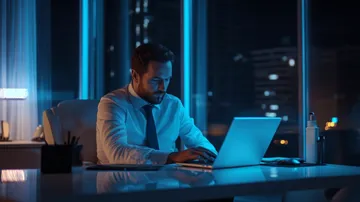 a man sitting at a desk using a laptop 