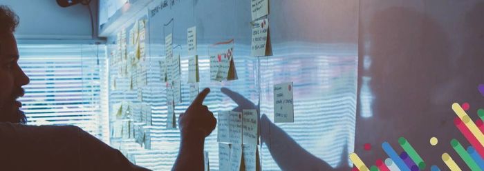 a person writing on a board with sticky notes