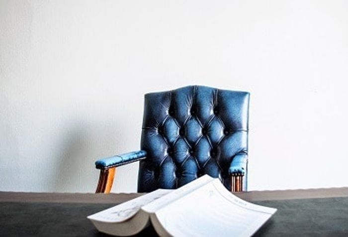 a blue chair sitting on top of a table next to a book