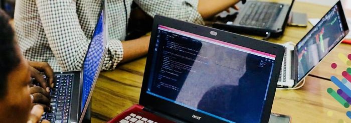 a group of people sitting at a table with laptops