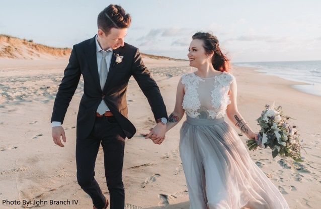 A bride and groom walking on the beach holding hands. Photo by: John Branch IV