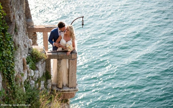 A bride and groom sitting on a balcony overlooking the ocean. Photo by: Sarah Edmunds