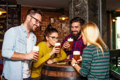 a group of people standing around a barrel drinking beer