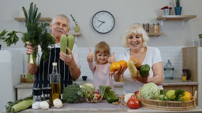 A man and a woman holding vegetables and giving thumbs up