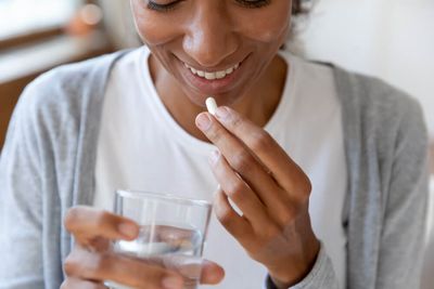 Prebiotic vs. probiotic: a woman holding a supplement pill.