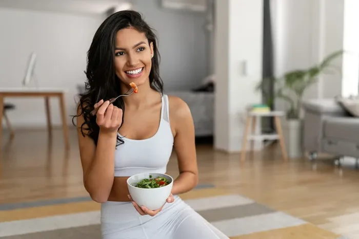 a woman is eating a bowl of salad being careful about her total cholesterol values