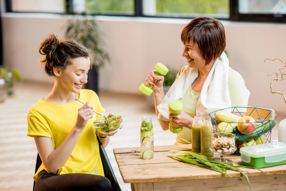 a younger and older women sitting at a table eating healthy food