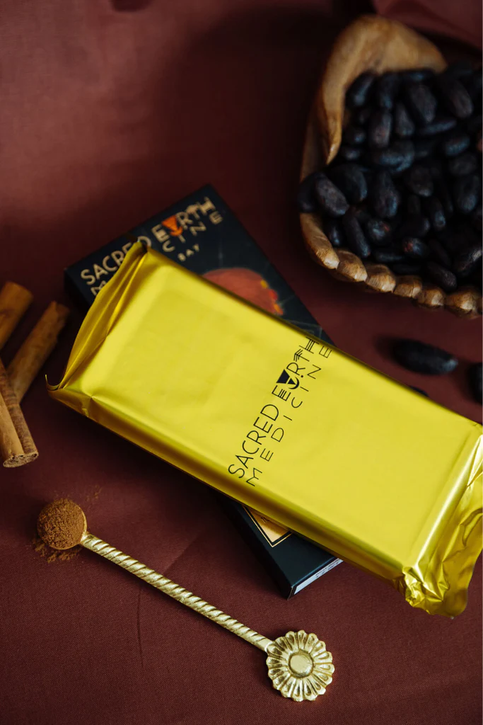 A bar of Sacred Earth Medicine Ceremonial Cacao next to some cacao beans.