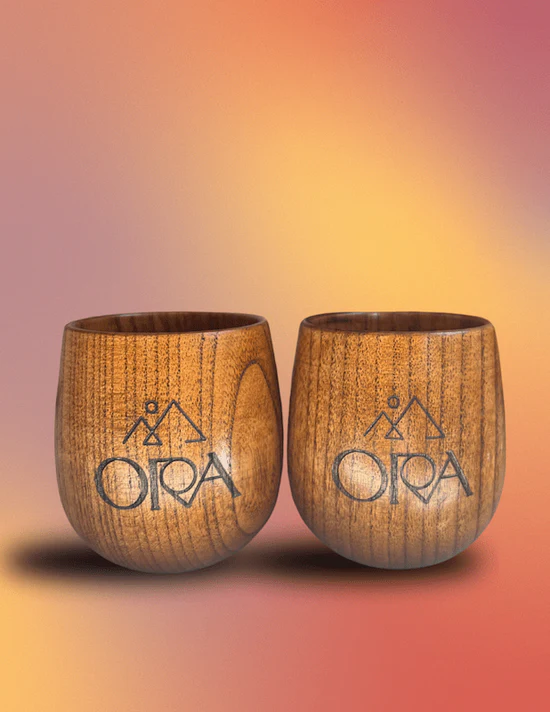 A couple of Ora Wooden Ceremonial Cacao Mugs sitting on top of a table.