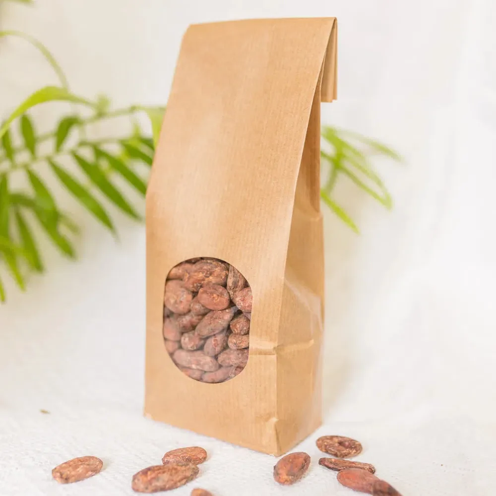 A brown paper bag filled with Herbal Cacao Ceremonial Cacao Beans.