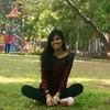 a woman sitting on the ground in a park