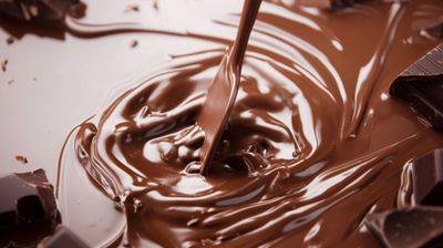 a spoon is pouring chocolate into a bowl