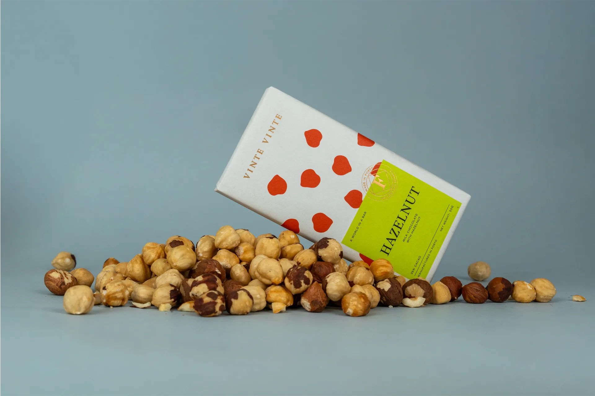 A slab ov Vinte Vinte Hazelnut Chocolate lying on a bed of hazelnuts.