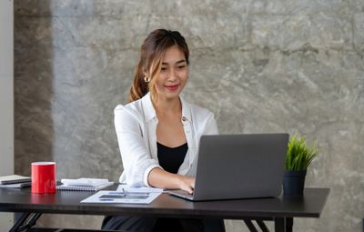 Young professional woman sitting at a desk while working on a laptop