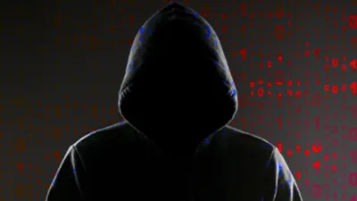 a hooded person standing in front of a red and black background